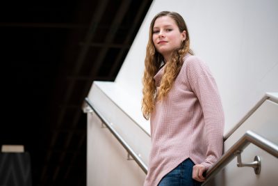 Amber Abbott, the 2020 Virginia Tech College of Science Outstanding Senior, poses in the New Classroom Building at Virginias Tech. She is wearing a sweater and leaning against a stairwell railing.